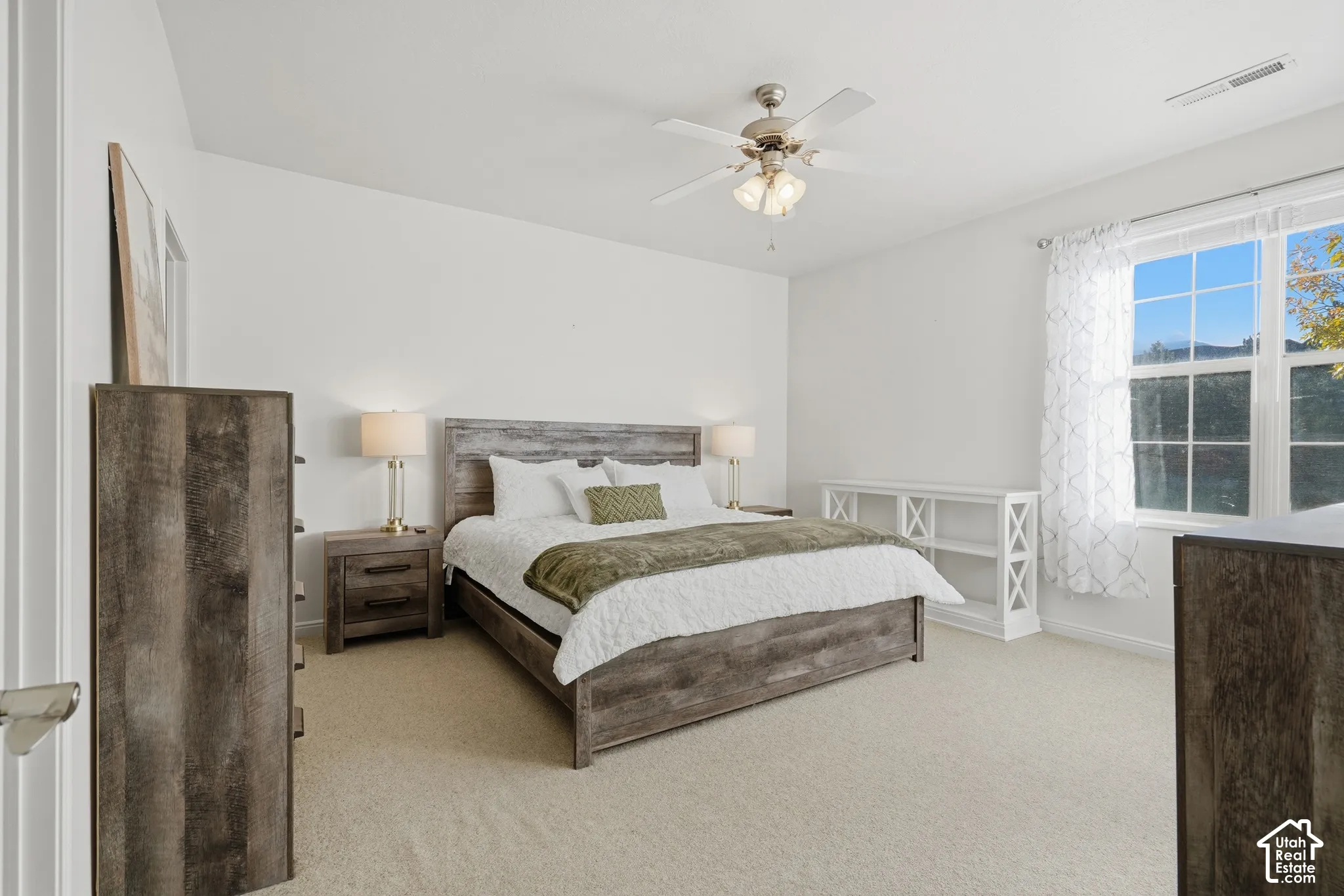Neutral wall palette featuring wall-to-wall carpeting, a multi-light ceiling fan, and large windows with muntin dividers