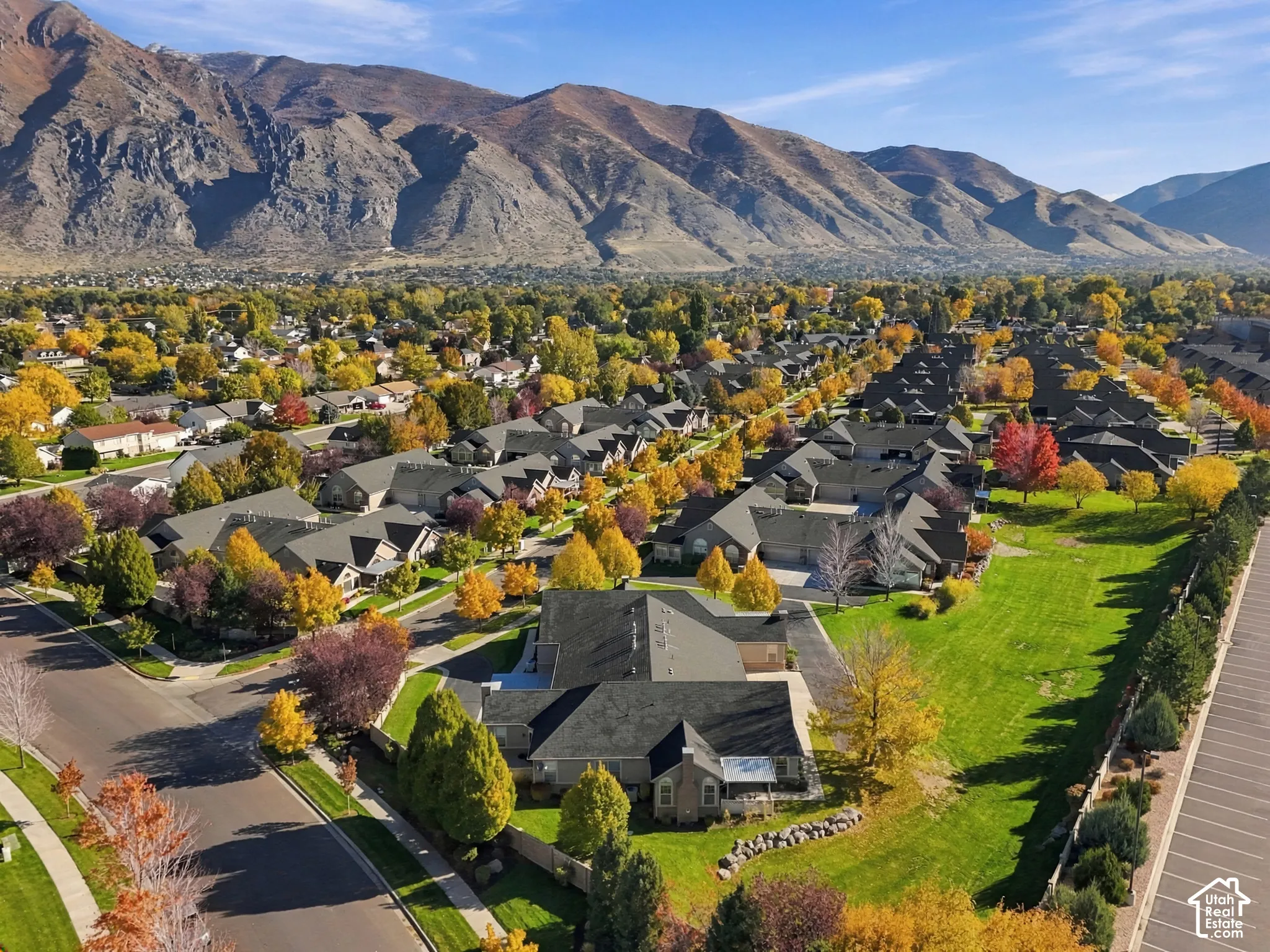 Aerial perspective featuring expansive mountain backdrop, residential landscape, mature trees, and street-level infrastructure