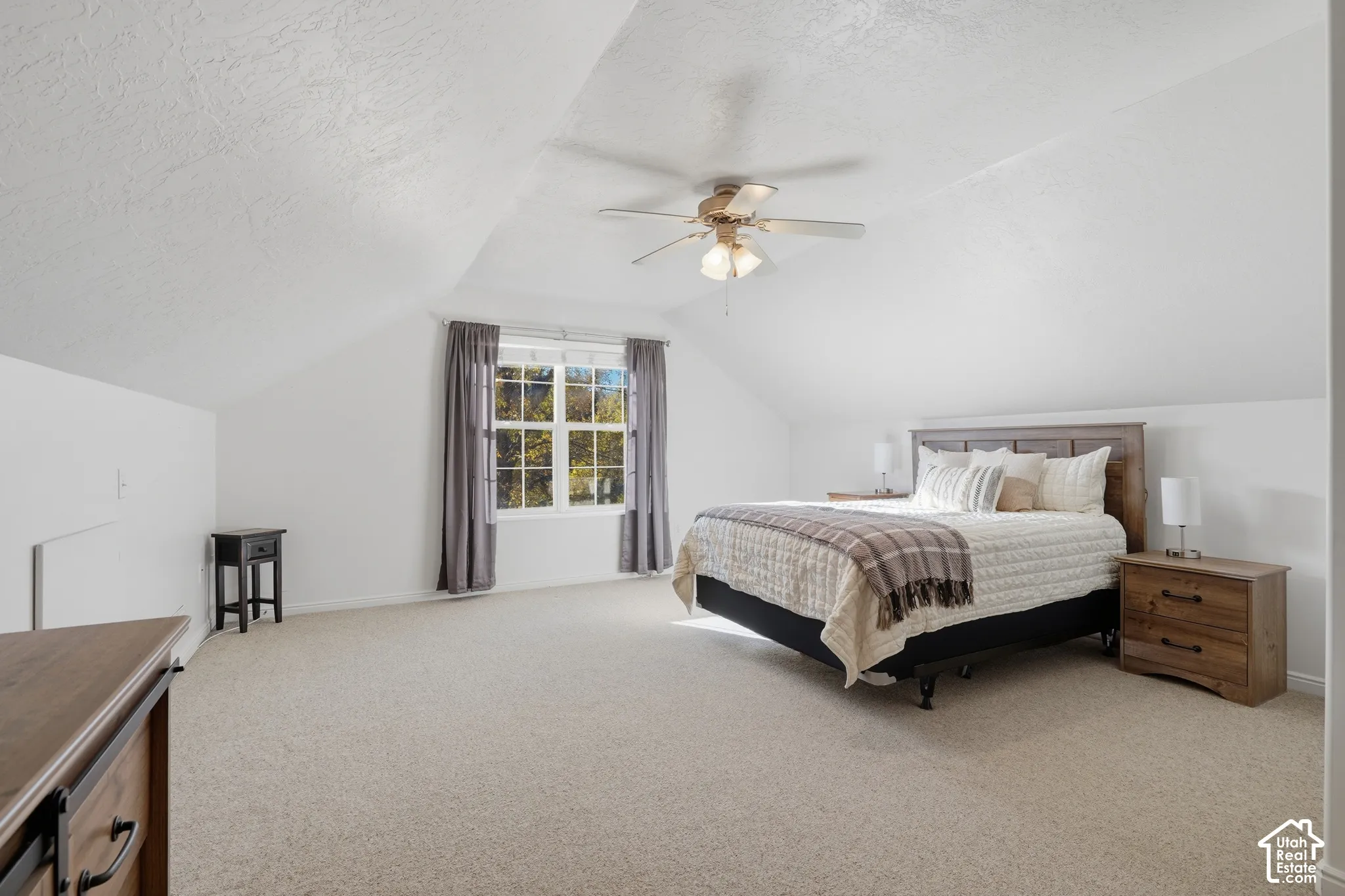 Vaulted ceilings, neutral carpeting, and a central ceiling fan fixture