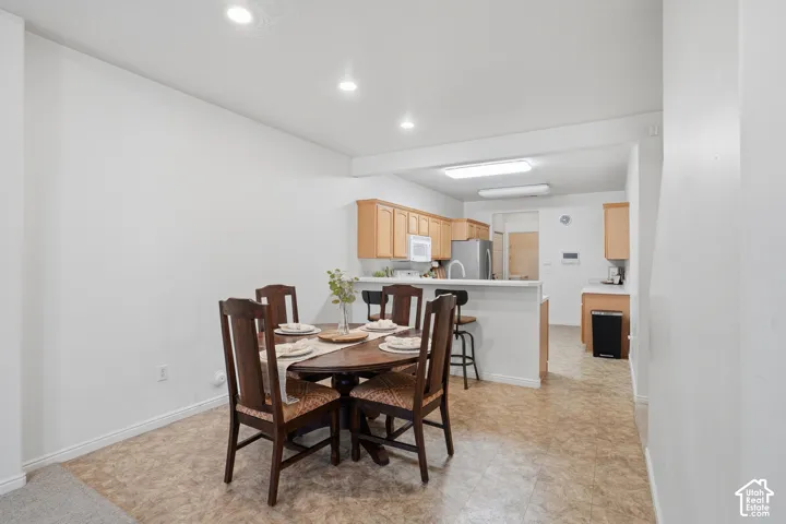 Kitchen area featuring cabinetry with wood-finish doors, a peninsula with an attached counter, recessed ceiling lighting, and tile-style flooring