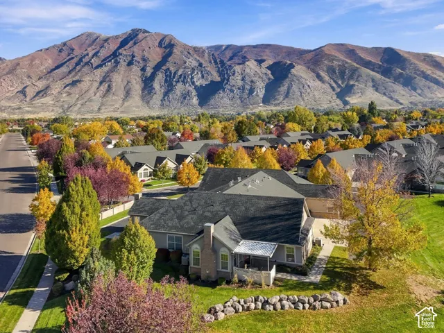 Aerial perspective featuring a multi-pitched roofline, stone-accented masonry chimney, and stone hardscaping, set against a backdrop of mountain scenery