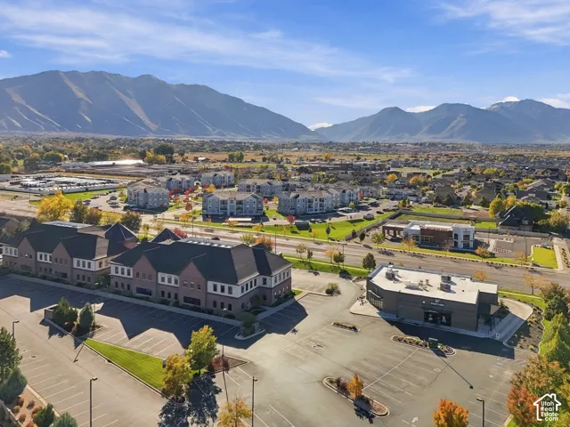 Aerial perspective of multi-story brick commercial structures with asphalt parking lots, mature landscaping, and prominent mountain backdrops
