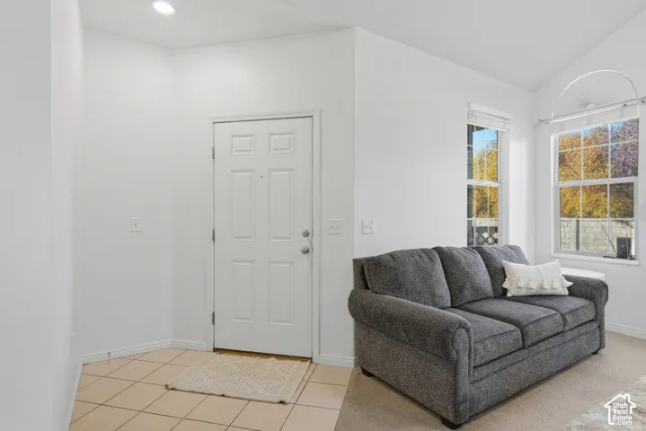 Vaulted ceilings, neutral tile flooring in the entryway, wall-to-wall carpeting, and double-pane windows