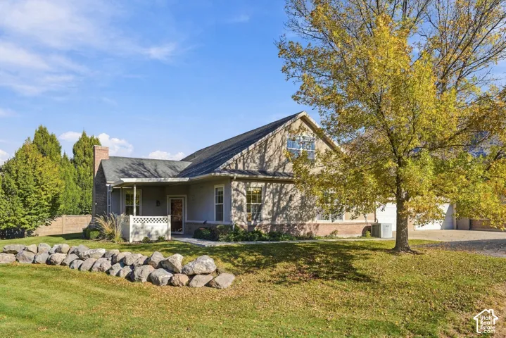 Traditional exterior featuring stone-accented siding, a brick chimney, a covered porch with lattice detail, and a multi-car garage