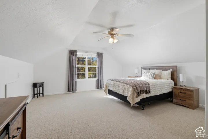 Vaulted ceilings, neutral carpeting, and a central ceiling fan fixture