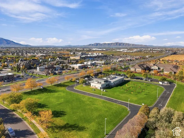 Expansive lot featuring paved circular access, manicured green space, mature tree plantings, and mountain scenery