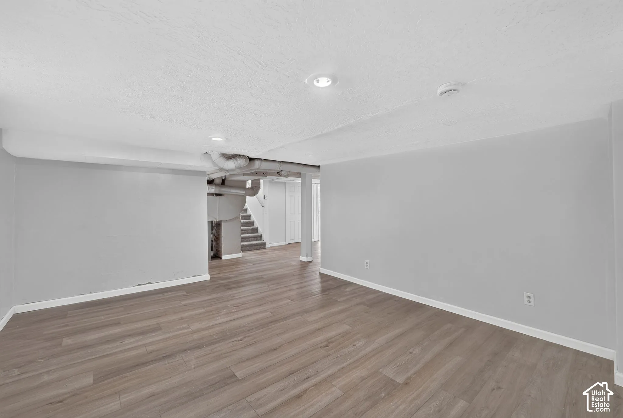 Open-concept interior space featuring wood-finish flooring, recessed lighting, and neutral wall paint