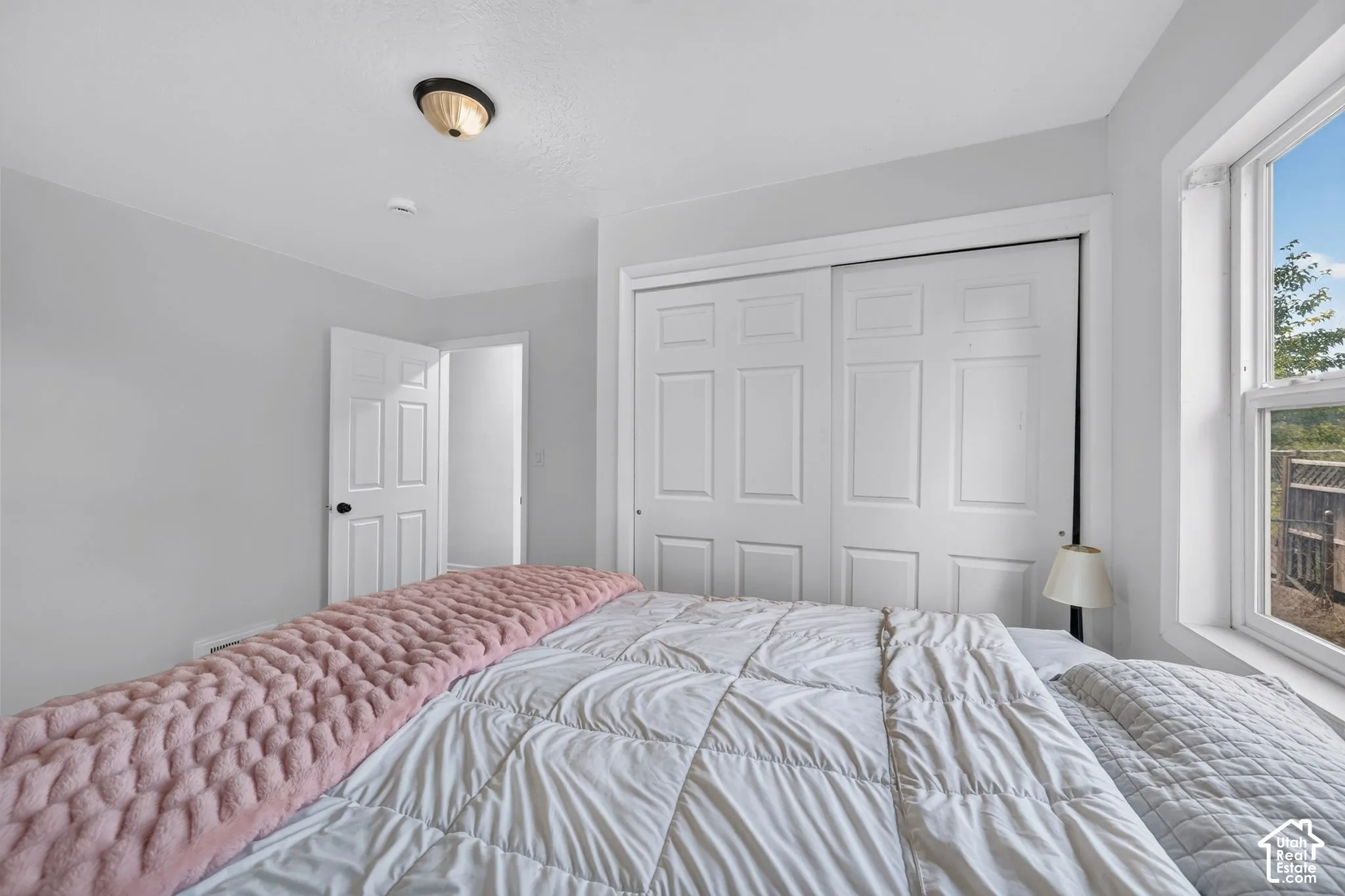 Neutral-toned room featuring a sliding-door closet, multi-panel doors, a single-hung window, and a flush-mount ceiling light fixture