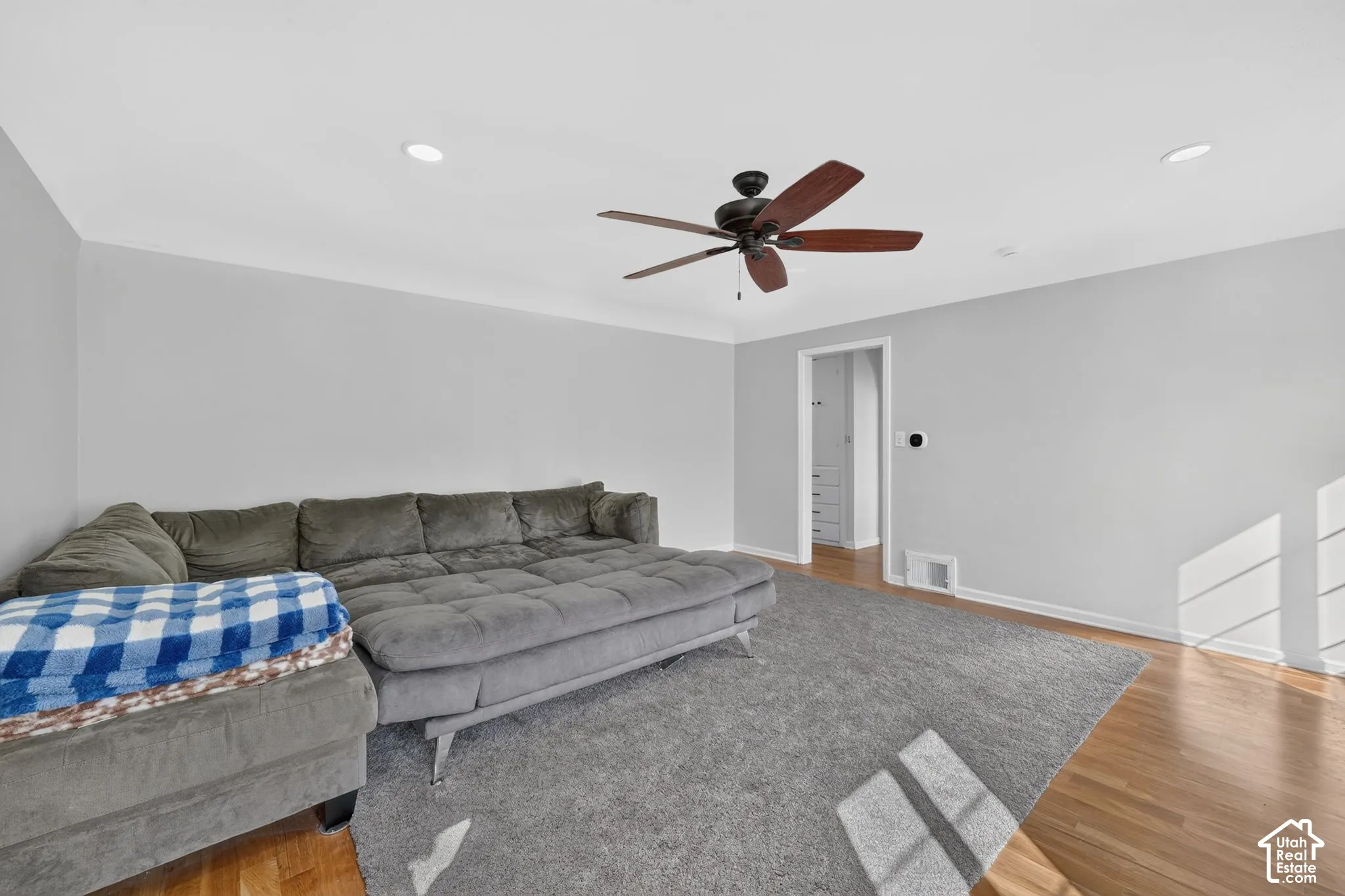 Neutral wall tones, recessed lighting, wood-finish flooring, and a ceiling fan with integrated lighting