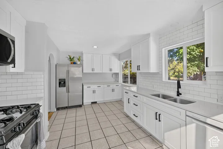 Kitchen featuring white cabinetry with matte black hardware, stone-finish countertops, white subway tile backsplash, and ceramic tile flooring
