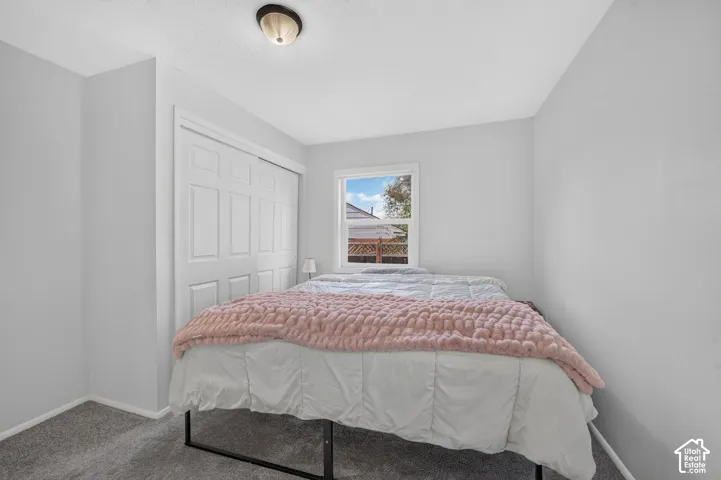 Neutral-toned interior featuring wall-to-wall carpeting, a multi-panel closet door, a single-hung window with white trim, and a semi-flush mount ceiling light fixture
