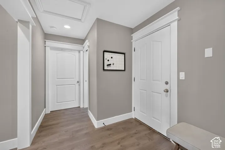 Entryway featuring wood-finish flooring, white paneled interior doors, and custom door casing with header trim details