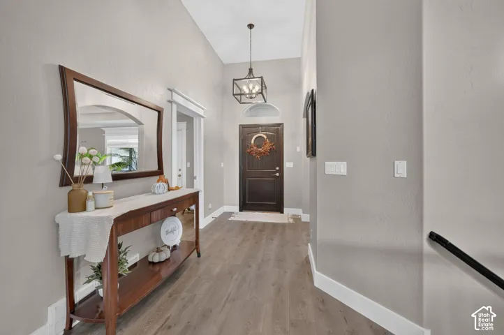 Foyer featuring high ceilings, wood-finish flooring, a dark-stained wood front door with a transom window, and a hanging geometric lantern fixture
