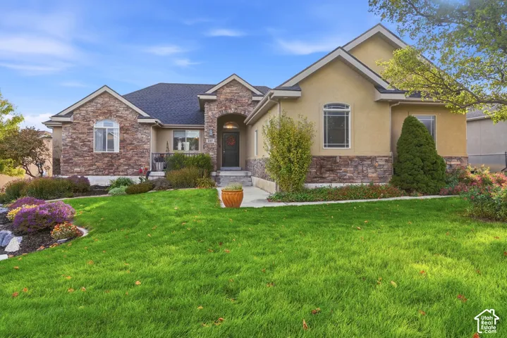 Exterior facade featuring multi-textured stone masonry and stucco siding, gabled rooflines, arched entryway, and manicured landscaping