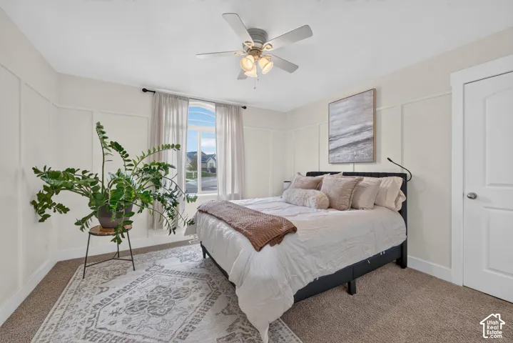 Room featuring wainscoting wall paneling, an arched window, and a ceiling-mounted light fixture with a fan