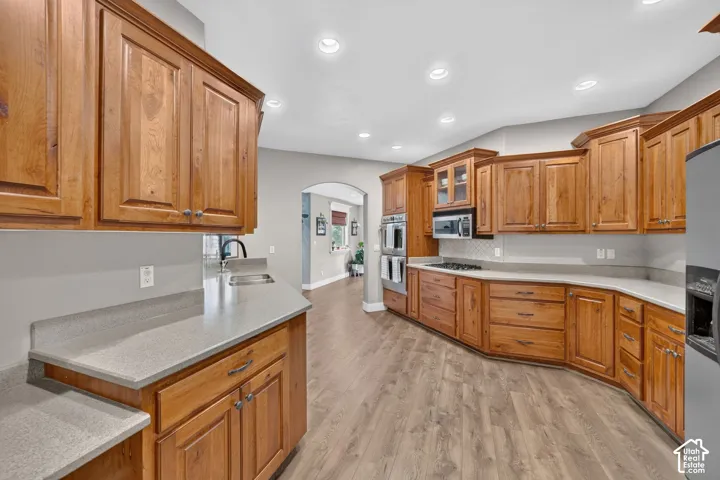 Kitchen featuring stained wood cabinetry, stone-surface countertops, built-in double wall ovens, recessed lighting, and wood-finish flooring