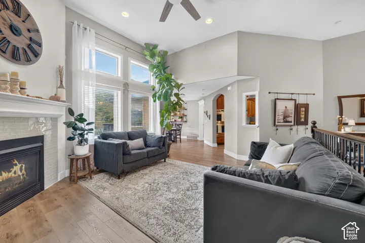 Vaulted ceilings, fireplace with tile surround, wood-finish flooring, floor-to-ceiling windows, and recessed lighting