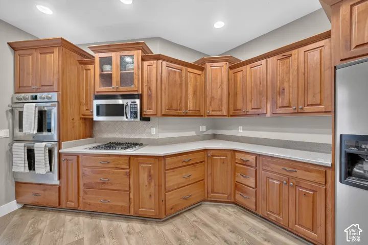 Kitchen featuring custom wood cabinetry, stone countertops, stainless steel double wall ovens, a gas cooktop, and herringbone-patterned flooring