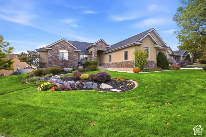 Exterior featuring stone veneer siding, stucco finish, arched entryway, and landscaped garden beds with stone retaining walls