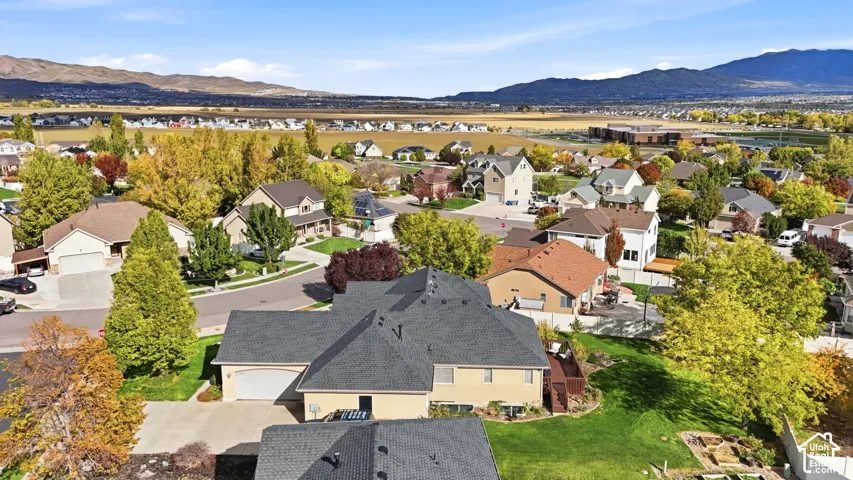 Aerial perspective featuring a multi-gabled roofline, attached multi-car garage, concrete driveway, and expansive mountain scenery