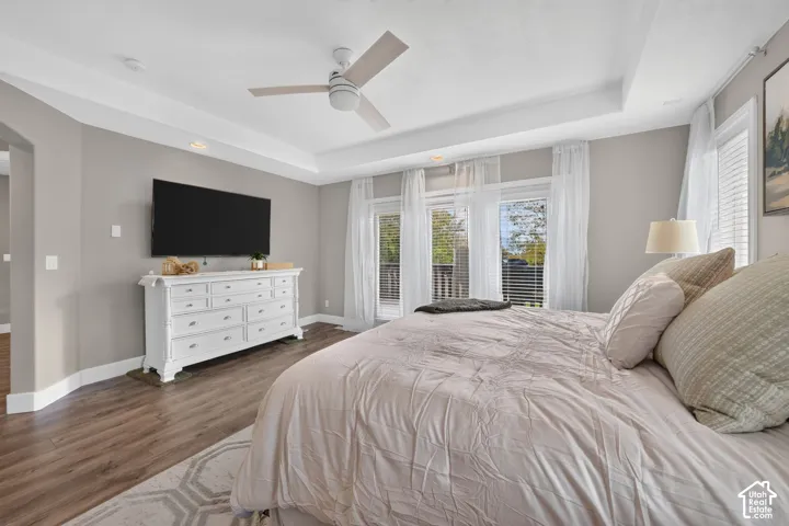 Tray ceiling with recessed lighting, wood-finish flooring, ceiling fan, and double-glass paneled doors