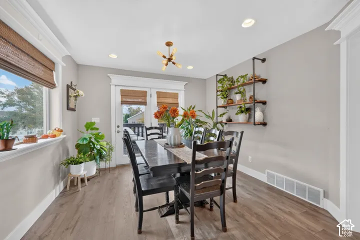 Dining area featuring wood-finish flooring, recessed lighting, a multi-arm industrial-style chandelier, and wall-mounted industrial pipe shelving