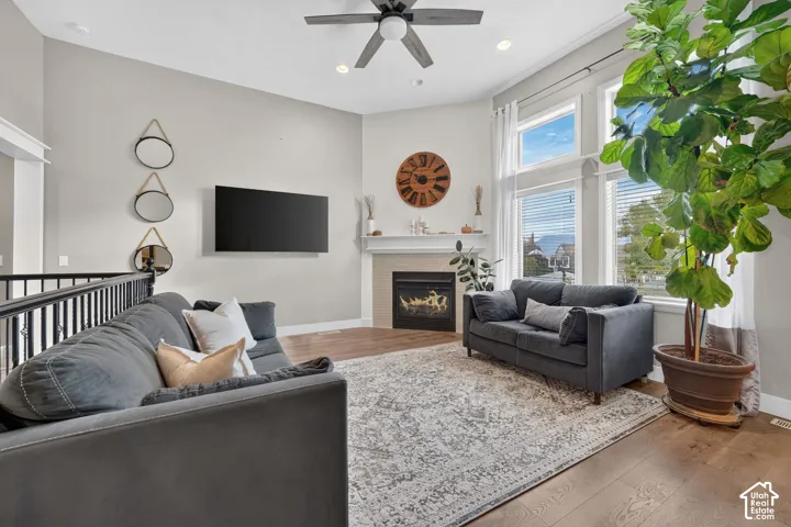 Living area with vaulted ceilings, wood-finish flooring, fireplace with a tile surround and mantel, and large windows with transoms