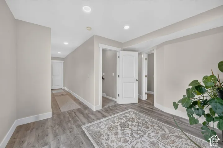 Neutral-toned interior hallway featuring wood-finish flooring, recessed lighting, and white arched-panel doors