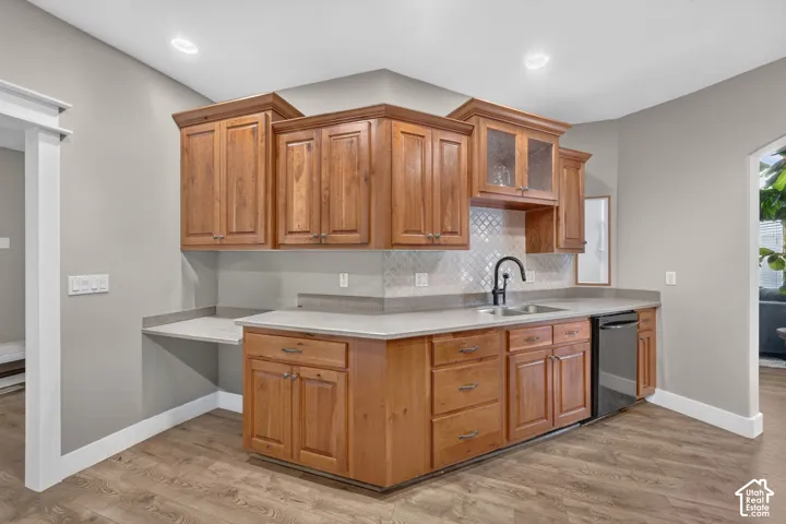 Kitchen featuring stained wood cabinetry, stone-finish countertops, geometric tile backsplash, recessed lighting, and a high-arch matte black faucet