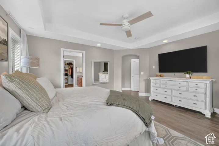 Tray ceiling with recessed lighting, ceiling fan, and wood-finish flooring