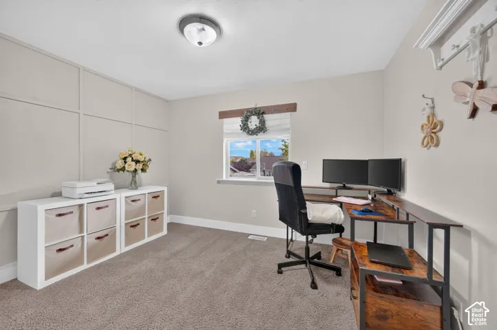 Room featuring neutral wall-to-wall carpeting, decorative wall molding, a sliding window with a wooden header, and a mounted wall hook system