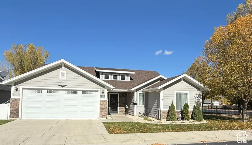 Single-story exterior featuring horizontal siding, stone veneer accents, a shingled gable roof, and a two-car attached garage
