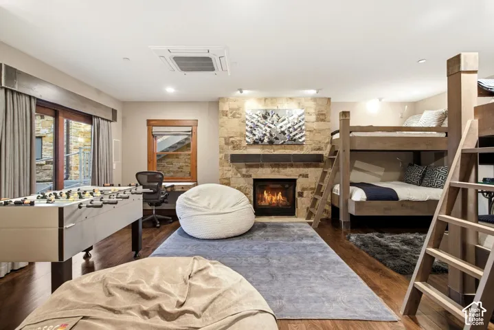 Stone-faced fireplace with a mantel, wood-finish flooring, and recessed ceiling lighting