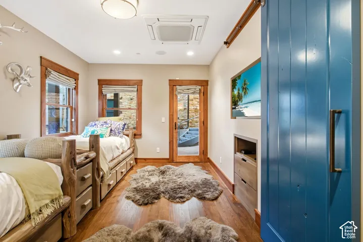 Wood-finish flooring, custom wood window and door casing, blue painted sliding barn door, built-in recessed cabinetry, and recessed ceiling lighting