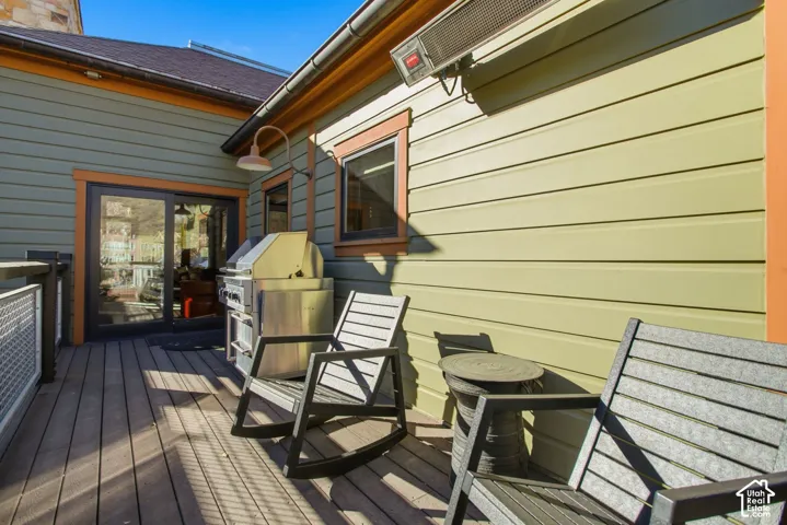 Exterior deck featuring horizontal lap siding, a built-in stainless steel grill, an overhead mounted heating unit, and a metal railing system