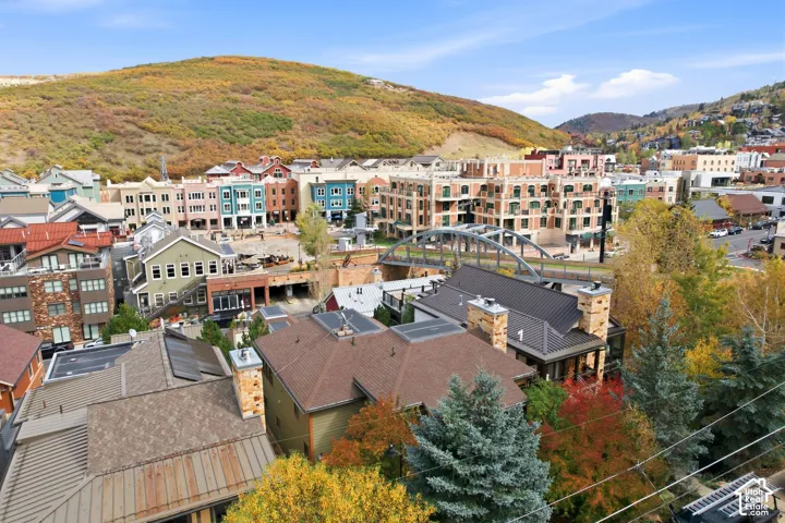 Aerial perspective featuring multi-story residential structures with pitched roofing, exterior stone chimneys, and metal roofing accents set against a mountain backdrop