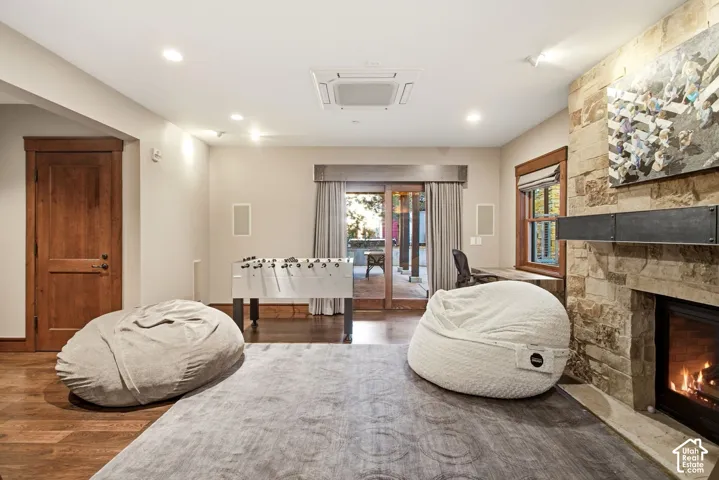 Floor-to-ceiling stone fireplace with a metal mantel, wood-finish flooring, recessed lighting, and wooden door and window casing