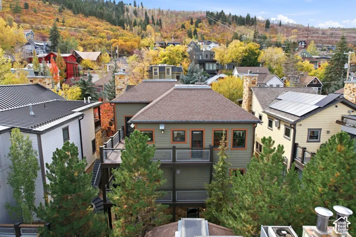 Multi-level residential structure featuring multi-tiered exterior decking with metal railings, horizontal lap siding, and stone-finished chimney masonry