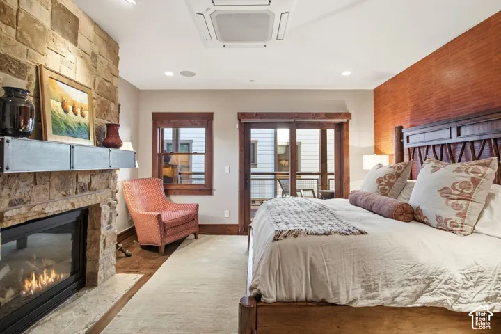 Floor-to-ceiling stone fireplace with a metal mantel, recessed ceiling-mounted climate control unit, stained wood window and door casings, and sliding glass doors