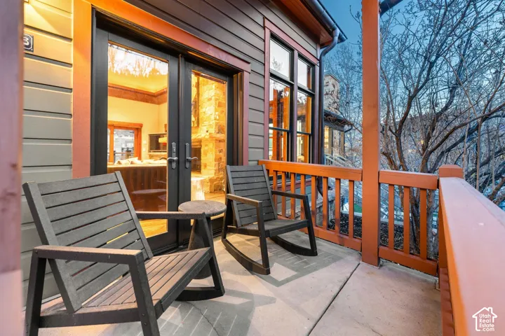 Covered porch featuring lap siding, double glass-paneled doors, wooden railings, and concrete flooring
