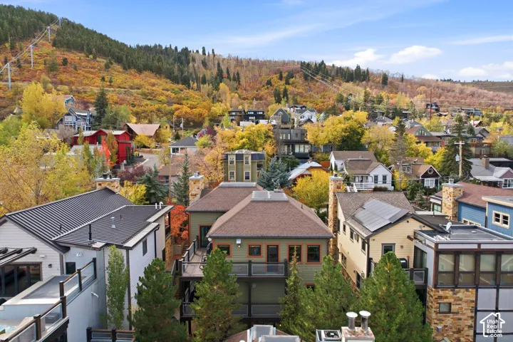 Multi-story residences featuring shingle and metal roofing, stone chimney stacks, and elevated wooden decking