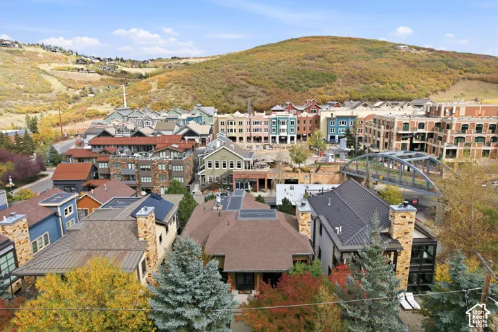 Aerial perspective of a mountain community featuring multi-story structures, stone masonry siding, metal roofing, and solar panel arrays
