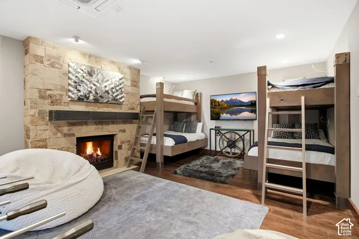 Floor-to-ceiling stone-clad fireplace featuring a built-in firebox and a metal mantel, recessed lighting, and wood-finish flooring