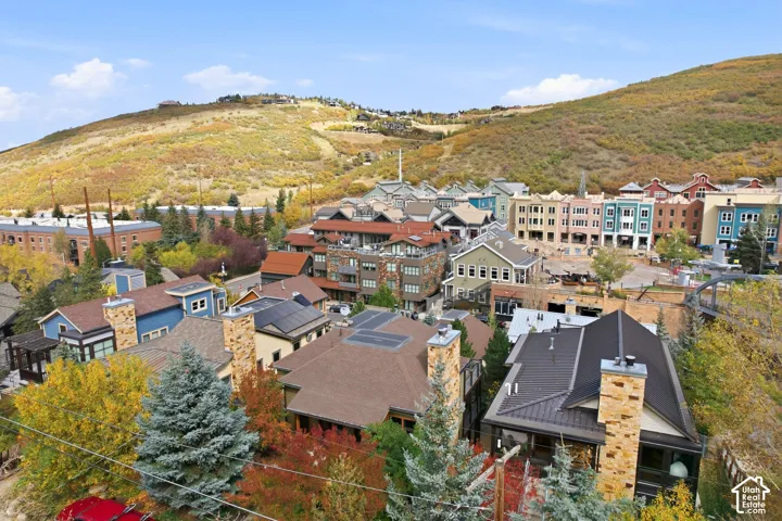 Aerial perspective featuring multi-story mountain residences with stone masonry chimneys, metal roofing systems, roof-mounted solar panels, and surrounding mature coniferous and deciduous trees