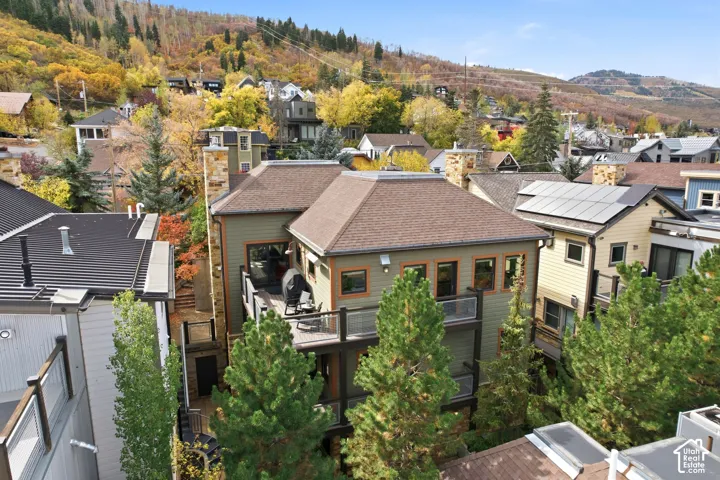 Multi-level exterior featuring wood-finish siding, two stacked decks with metal railings, a stone-clad chimney, and a mountain backdrop