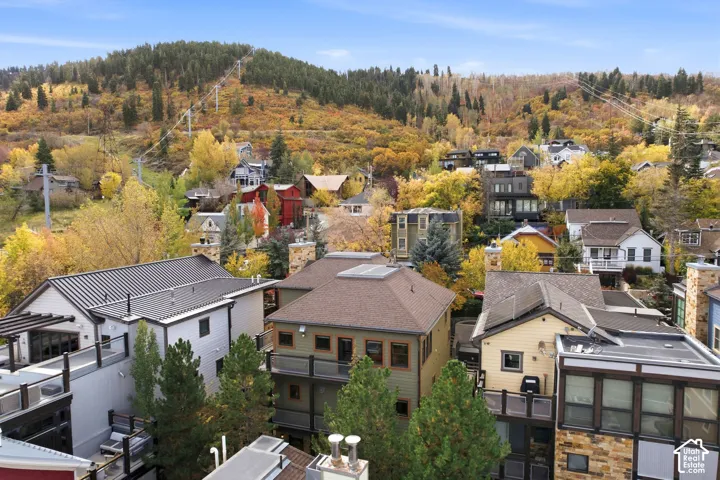 Elevated hillside setting featuring mature trees, wooded mountain terrain, and custom residential architecture with multi-level decks