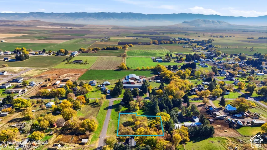 Aerial perspective of a parcel featuring established deciduous trees and expansive mountain backdrops