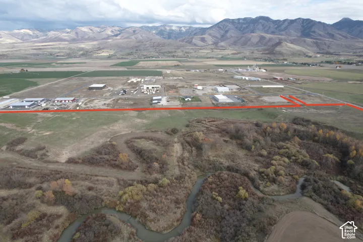 Expansive undeveloped acreage featuring natural riparian vegetation, a winding creek, and mountain terrain backdrop