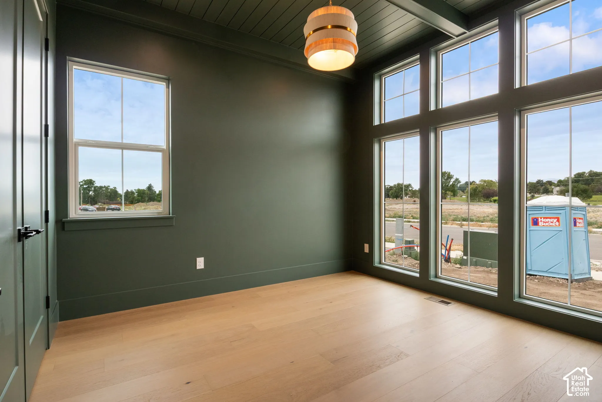 Room featuring wood-finish flooring, floor-to-ceiling windows with mullions, tongue-and-groove paneled ceiling, and a tiered pendant light fixture