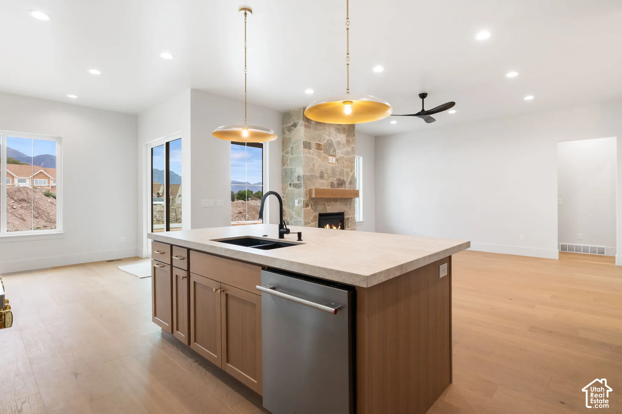 Kitchen island with light-finish cabinetry, solid surface countertop, and integrated stainless steel dishwasher